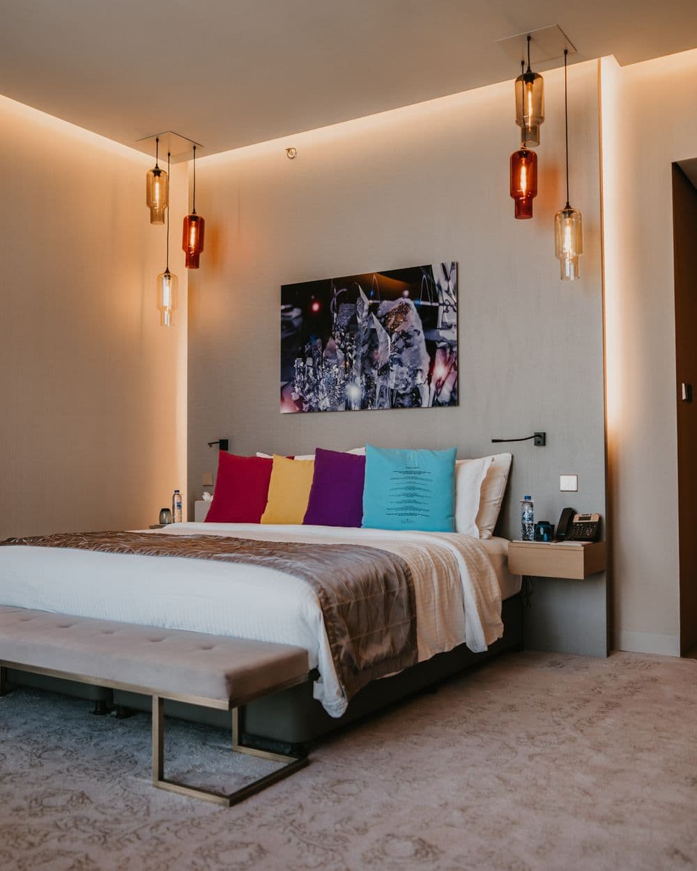 Hotelzimmer mit farbigen Kissen und Glasleuchten